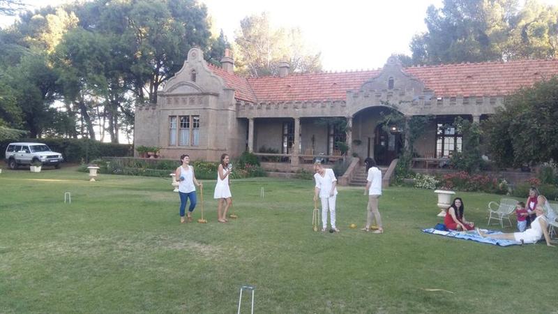 A group playing croquet on the lawn in front of the homestead
